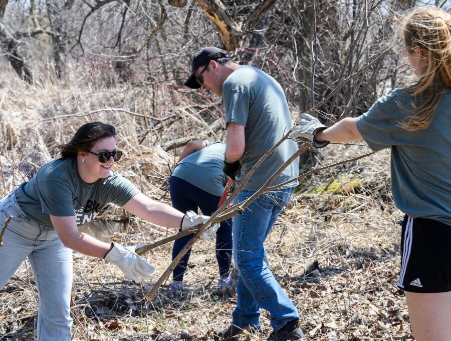 Volunteers wearing matching green T-shirts work to remove brush from the Lakeshore Nature Preserve.