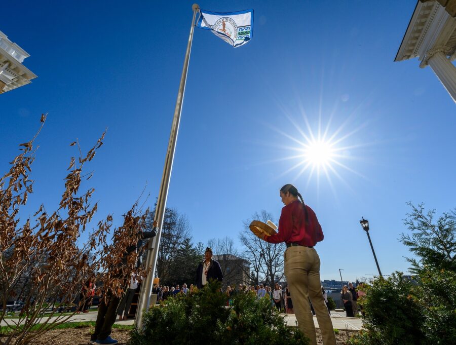 From right to left, Cordell Funmaker, Ho-Chunk Nation tribal member; Marcus WhiteEagle, Ho-Chunk marine veteran; and Marlon WhiteEagle, president of the Ho-Chunk Nation and marine veteran; play the hand drum and raise the Ho-Chunk Nation’s flag in front of Bascom Hall at the University of Wisconsin–Madison on April 12, 2023.