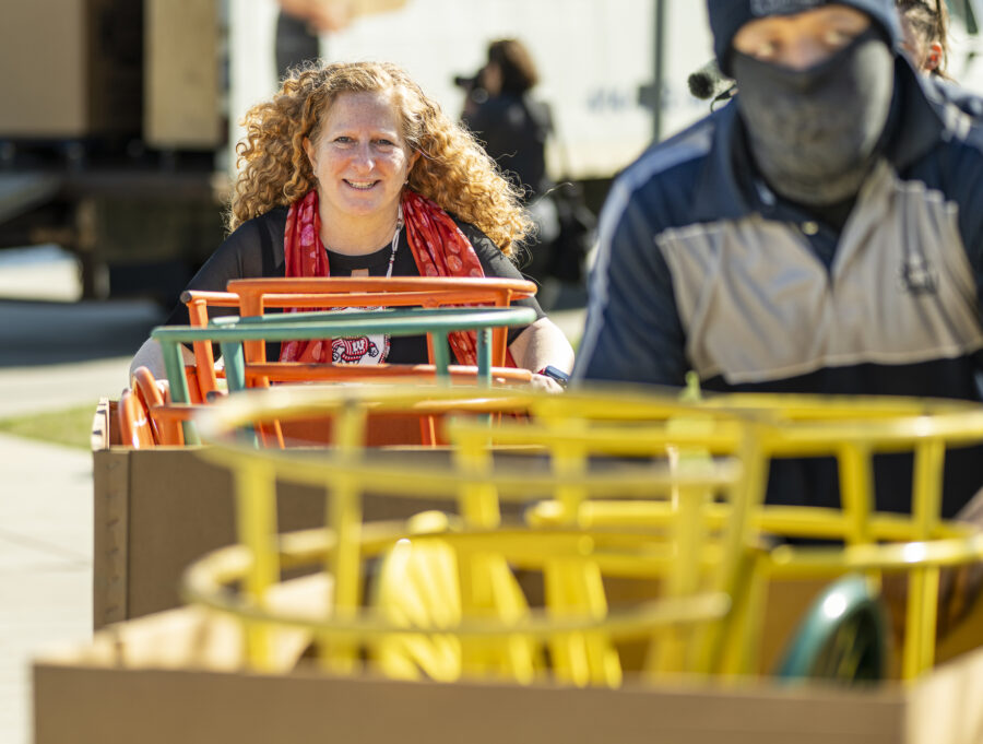Jennifer Mnookin pushes a trolly loaded with metal chairs across a sunny, crowded Memorial Union Terrace.