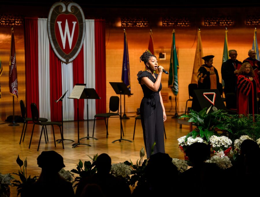A woman holds a microphone and sings.