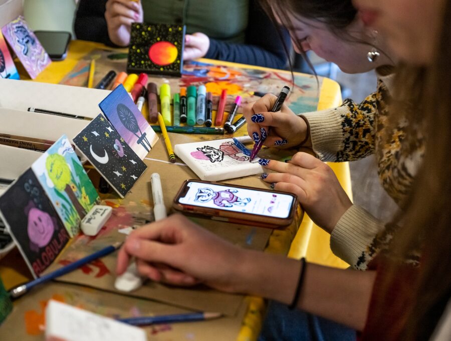 People's hands can be seen working on creating tiles for the mural project.